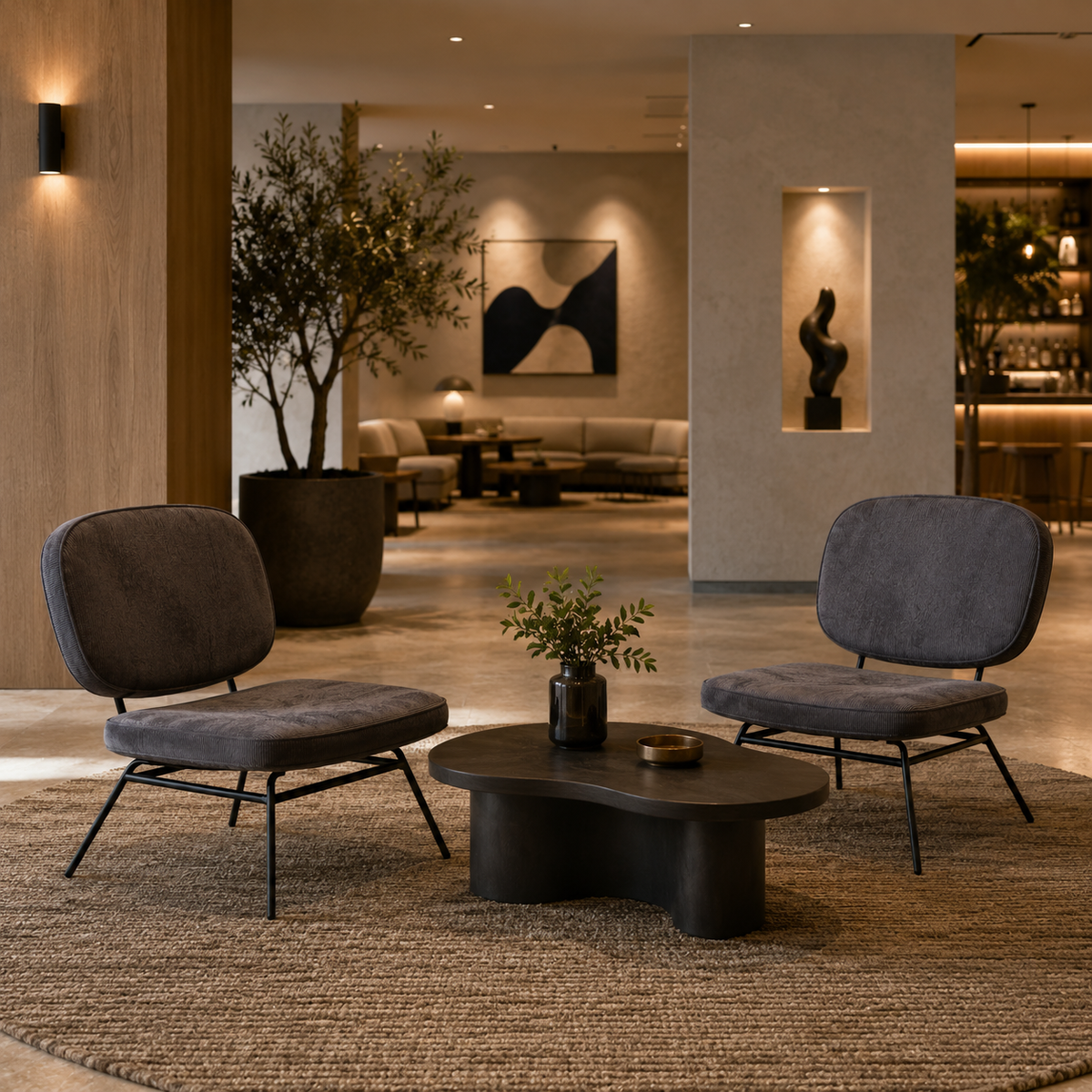 Two Graphite corduroy lounge chairs in a boutique hotel lobby with oval coffee table and warm ambient lighting RC-01