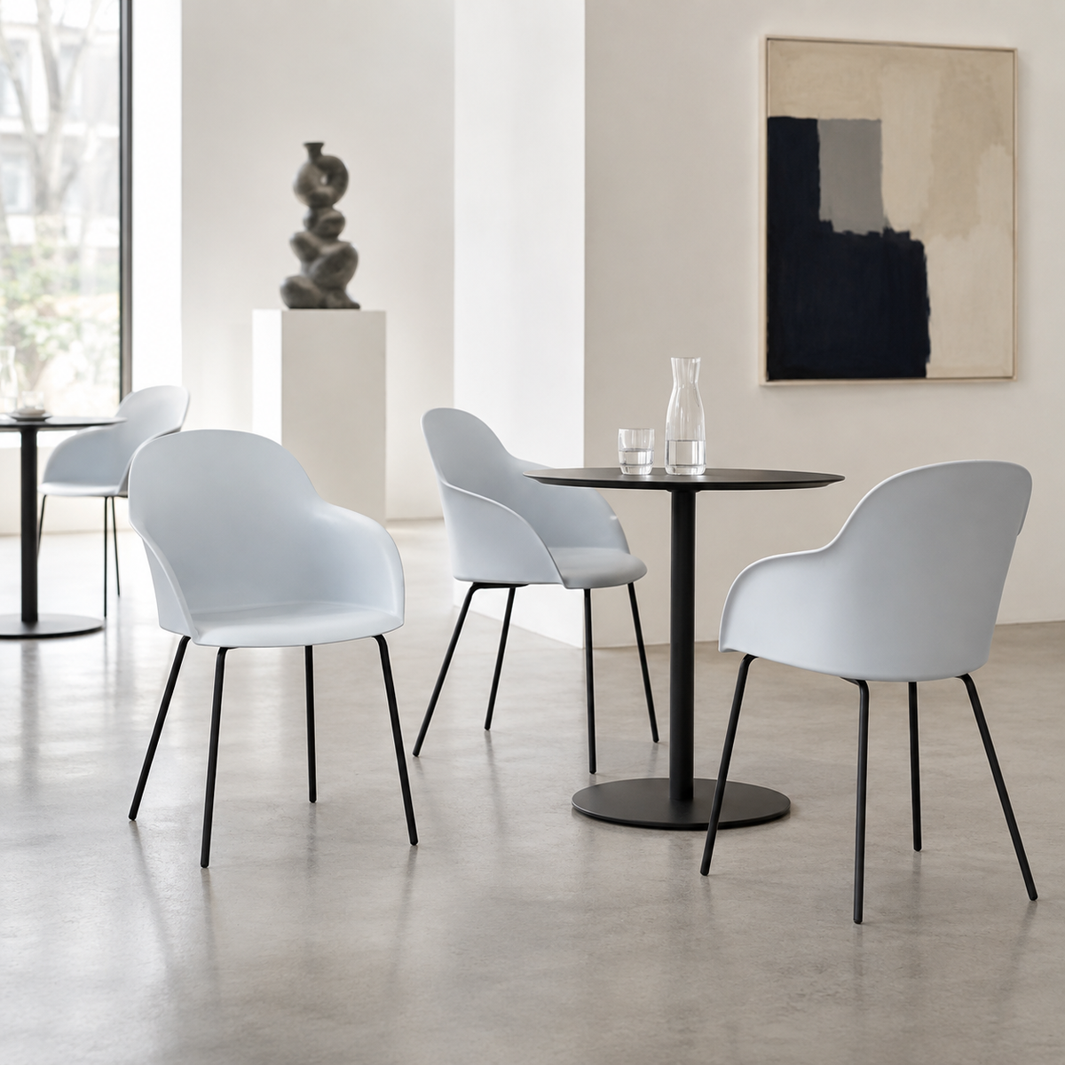 Pale blue grey shell-back polypropylene dining armchairs around a black round table in a minimalist design studio interior PC-16