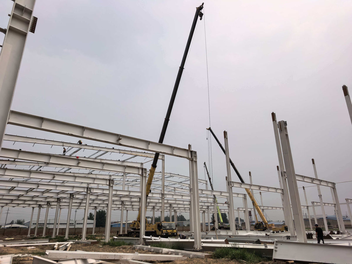 Cranes assembling steel beams for GEYA’s future production workshop frame.