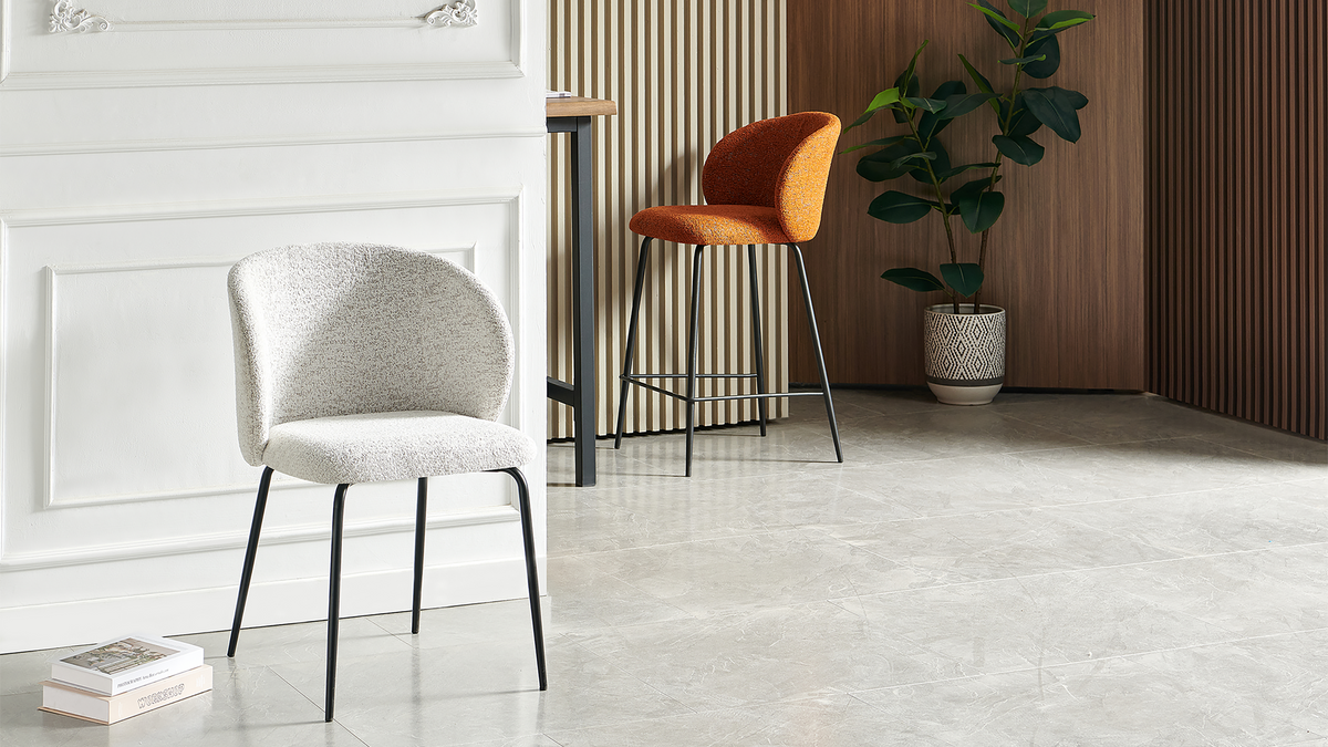 Bouclé bar stool in rust brown beside a light upholstered chair, showing a rounded wraparound back and black front footrest, BC-107