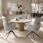 Ash grey bouclé high-back swivel armchairs around round oak table in design studio with material sample wall and glazed partition — DC-5035

