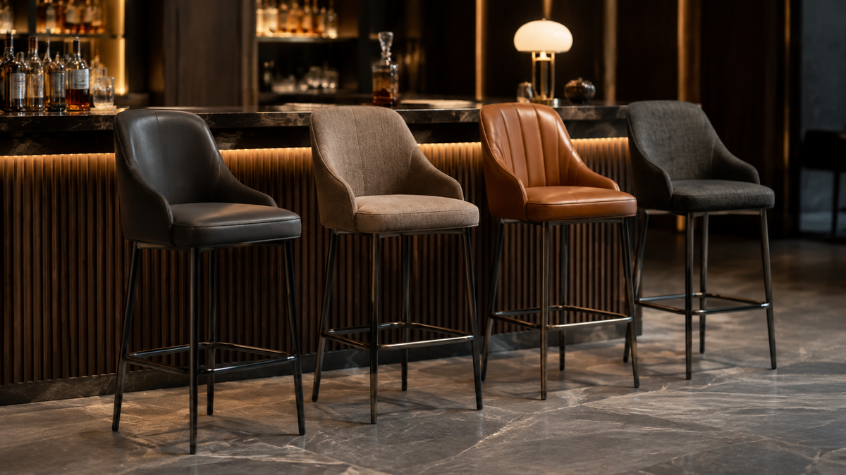 Commercial bar stools with supportive upholstered backs, slim metal frames and integrated footrests in a hospitality bar setting.