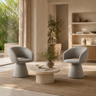 Melange woven pedestal swivel lounge armchairs in a boutique hotel reception area with a round low table, warm neutral interior, and soft natural daylight.