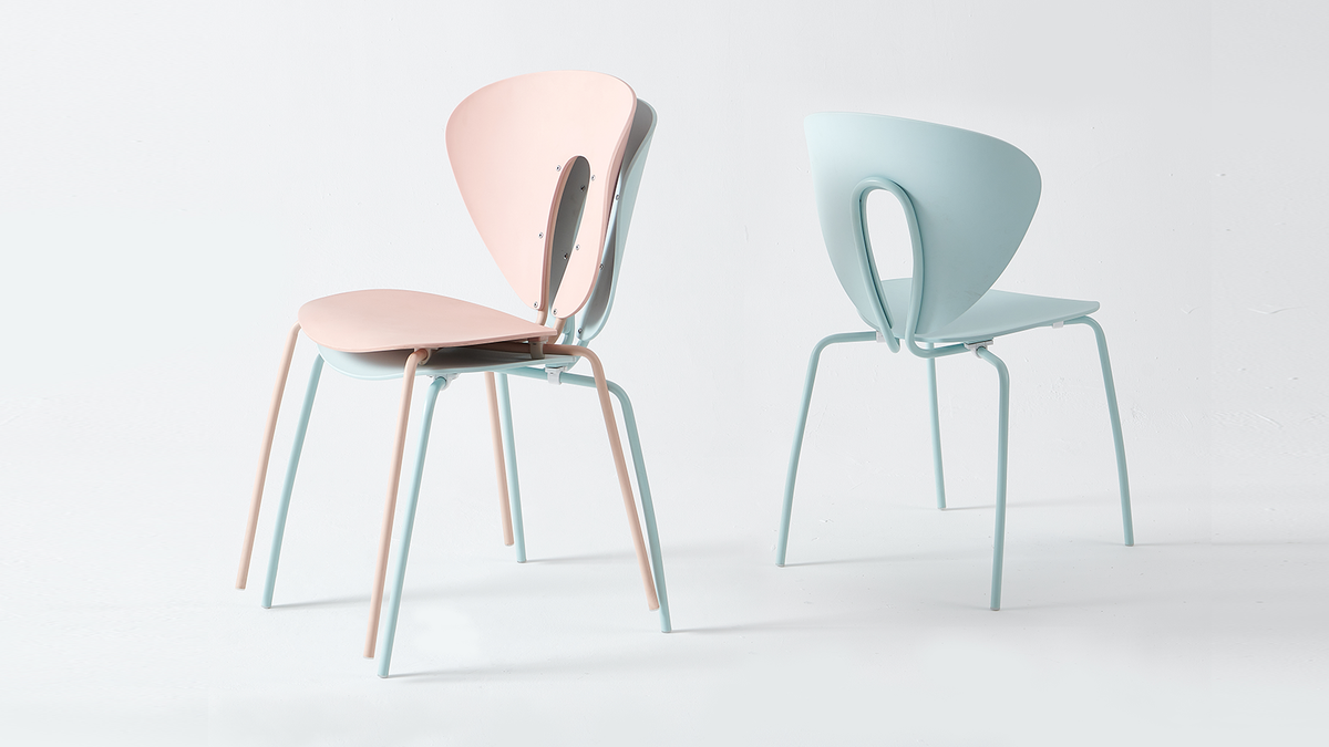 Two stackable cut-out back polypropylene side chairs in blush pink and pale mint shown stacked from rear, PC-96